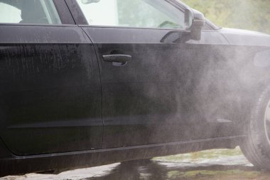 Yüksek basınçlı su kullanarak arabayı temizlemek. Açık hava. 