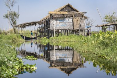  Myanmar, Inle Gölü 'nün sularını yansıtan ayaklıklar üzerinde geleneksel bir evden manzara.