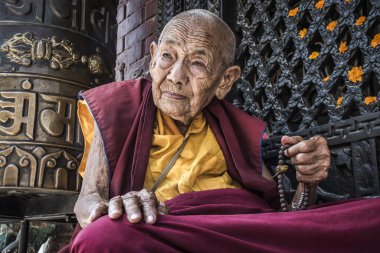 Bodnath, Katmandu, Nepal - Eylül 09 2017: Bodnath stupa, Katmandu, Nepal önünde dua eden yaşlı bir Nepalli Budist rahibenin portresi.