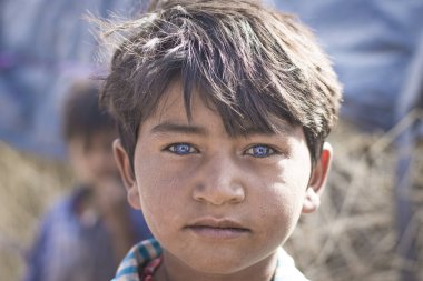 Jaisalmer, India- 11 Nisan 2017: Thar Çölü 'ndeki köyünde Jaisalmer, Hindistan yakınlarındaki güzel mavi gözlü bir çingene çocuğun portresi.
