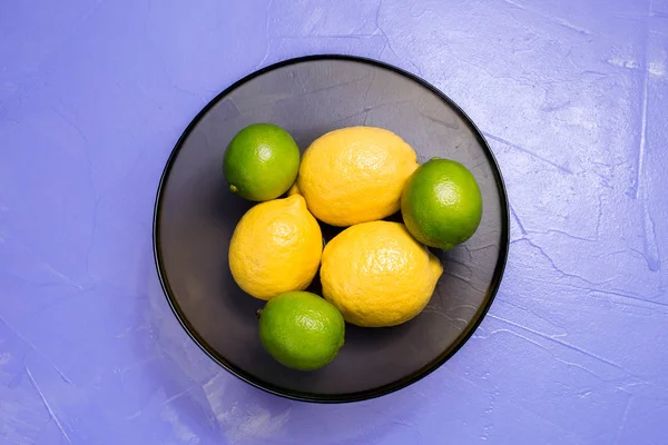 Limon ve limes Lila zemin üzerine cam kapta. Üstten Görünüm