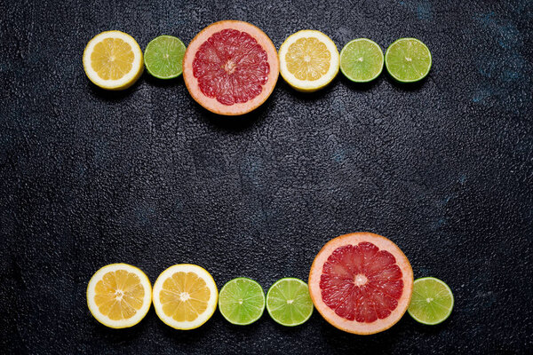 Rows of citrus: lemons, limes and grapefruit on dark background 