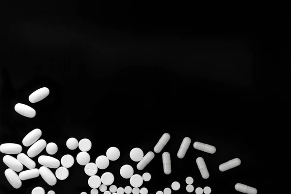 Kilka różnych tabletek biały na czarnym tle — Zdjęcie stockowe