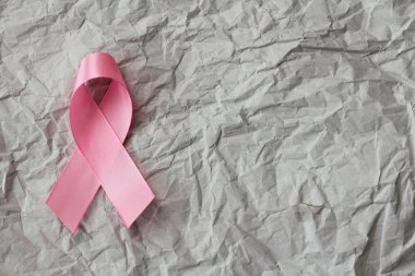 Pembe kurdele. Göğüs kanseri farkındalığının sembolü. Sağlık sigortası gebeliği. Önleyici önlemler. Ekim kontrol zamanı. Kadın sağlığı. Buruşmuş kağıt arkaplanı.