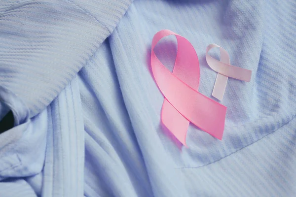 Pink ribbon. Symbol of breast cancer awareness. Health care conception. Preventive measures. October checking time. Women health. Blue cloth background.