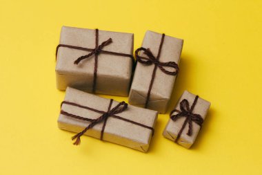 El işi kâğıdı ve kenevir ipine sarılı bir paket. Teslimat servisi. Çevrimiçi nakliye. Sarı, sağlam bir arka plan. Noel hediyeleri konsepti. Bir sürü hediye.