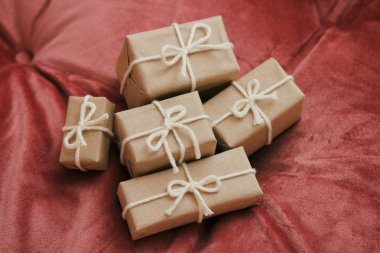 Noel için hediyeler. El işi kağıdına sarılı hediye kutuları ve beyaz ip. Kırmızı kadife kumaş arka plan. Tatil havası.. 