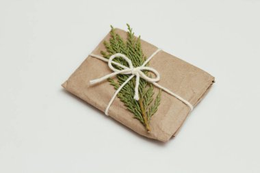 Kahverengi el sanatları kağıdına sarılı bir hediye kutusu ve beyaz bir ip. Noel havası. Beyaz, sağlam arka plan. Hediye paketi. Teslimat servisi. Yumuşak el çantası..