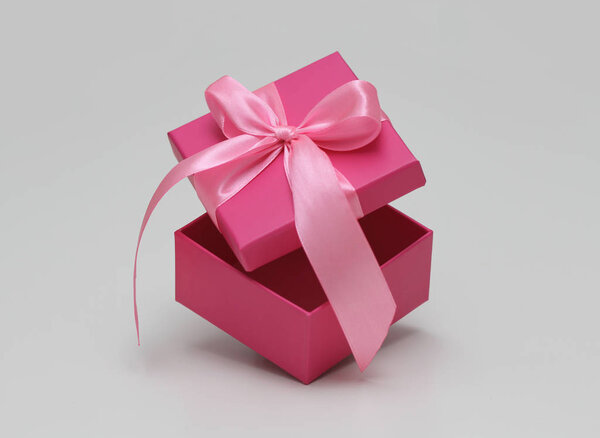 Розовая подарочная коробка с атласной лентой. Открыть движение. Пространство для товаров и текста. Процесс распаковки. Продажа шаблона купона. Белый фон
.