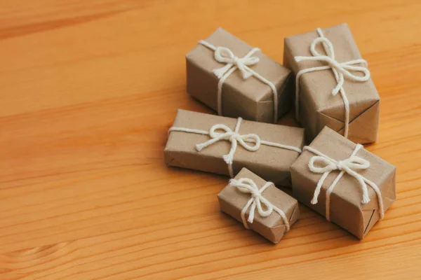 Set of parcels wrapping in brown craft paper and tie hemp string. Package. Delivery service. Online shopping. Your purchase. Gift box on a table. Isolation on white. Decorative wood background.