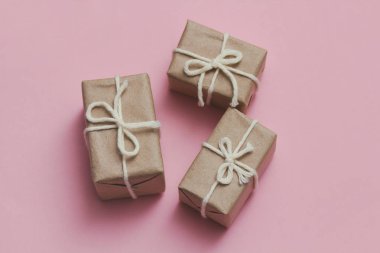 Kahverengi el işi kağıdına sarılı paketler ve kenevir teli. Paket var. Teslimat servisi. İnternetten alışveriş. Satın alın. Hediye kutusu masanın üstünde. Pembe katı arkaplan.