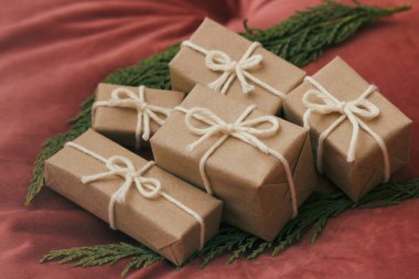 Noel için hediyeler. El işi kağıdına sarılı hediye kutuları ve beyaz ip. Kırmızı kadife kumaş arka plan. Tatil havası..