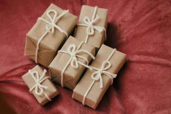 圣诞节的礼物 礼品盒用手工纸包好 系上白线 红色天鹅绒布背景 假日气氛 — 图库照片