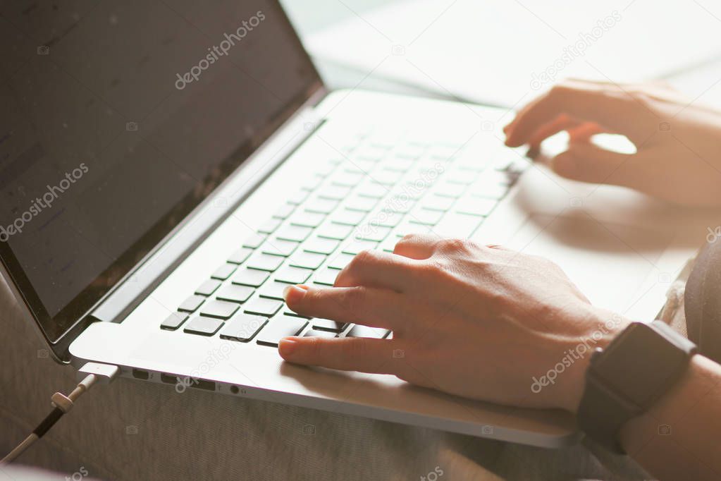 Young woman typing on a laptop keyboard. Close-up details. Girl's hands. Working online. Freelance concept. Shop on the couch. Online shopping.