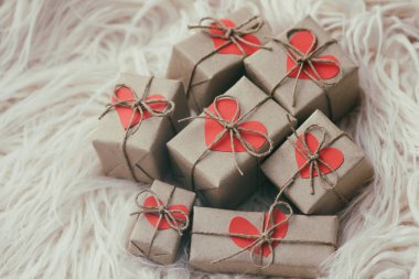 El işi kâğıdı ve kenevir ipine sarılı hediye kutuları. Kartondan kalplerle. Beyaz kürk arka planı. Yeni yıl. Noel havası. 