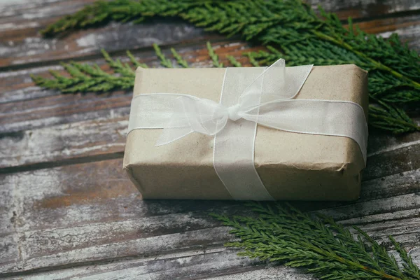 礼品盒用褐色工艺纸包好 系上白色缎带 圣诞气氛 装饰木背景 目前的一揽子计划 — 图库照片