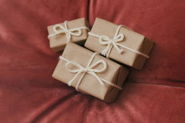 Noel için hediyeler. El işi kağıdına sarılı hediye kutuları ve beyaz ip. Kırmızı kadife kumaş arka plan. Tatil havası..