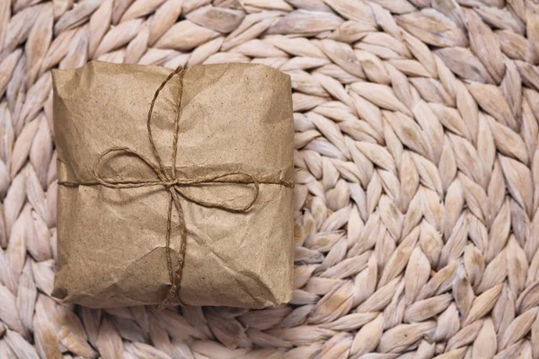 Parcel wrapping in brown craft paper and tie hemp string. Package. Delivery service. Online shopping. Your purchase. Gift box on a table. Decorative wood background.