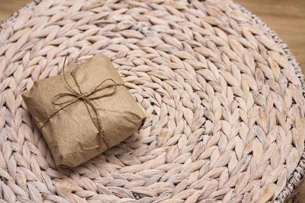 Parcel wrapping in brown craft paper and tie hemp string. Package. Delivery service. Online shopping. Your purchase. Gift box on a table. Decorative wood background.