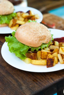 Hamburger ve patates kızartması beyaz bir plaka üzerinde