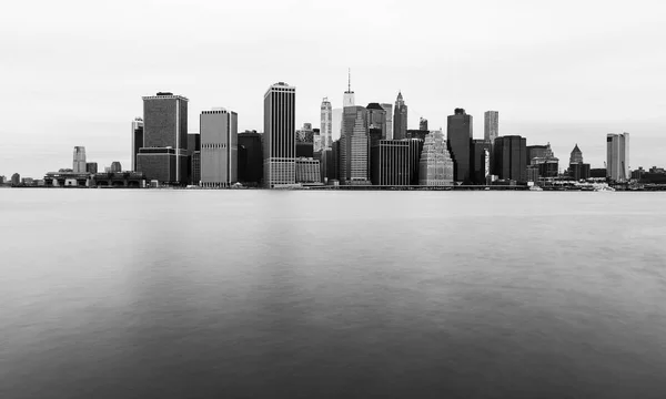 Manhattan siluetinin bulutlu günde New York gökdelen yansıyan su, siyah beyaz fotoğraf, ABD — Stok fotoğraf