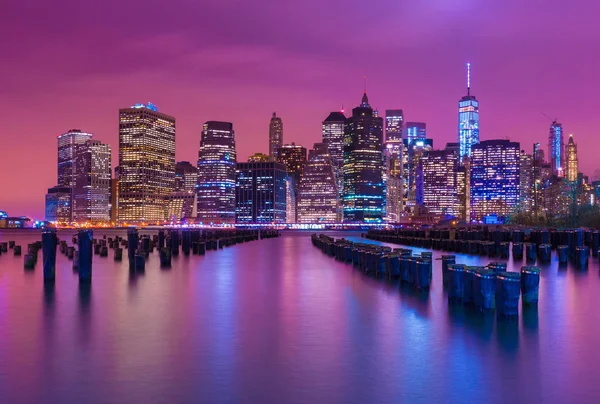 Manhattan skyline por la noche con reflejos varicolores en el agua, vista desde Brooklyn, Nueva York, EE.UU. — Foto de Stock