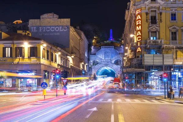 Trieste, Italy: Night view of the city of Trieste with car traffic lights trails, Pharmacy store and McDonalds building on Piazza Carlo Goldoni.