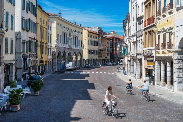 Udine, Italia: Calle Udine, la gente está en bicicleta en la calle principal del centro de la ciudad vieja en el día soleado del verano — Foto de Stock