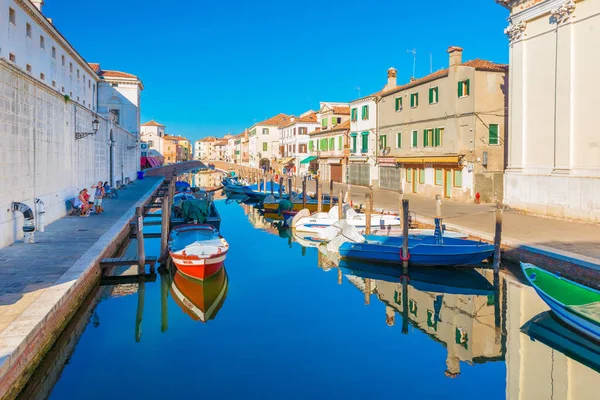 Chioggia, Italia: Canal con barcos en el agua en el centro histórico de Chioggia. La gente está caminando a lo largo del paseo marítimo, edificios y casas de estilo veneciano en la calle central de la ciudad —  Fotos de Stock