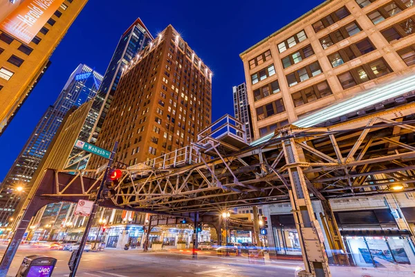 Chicago, EUA: Downtown Chicago à noite. Metro trem passando Wabash Avenue trilhas de luz viva. Prédios de escritórios no centro da cidade contra o céu azul profundo . — Fotografia de Stock
