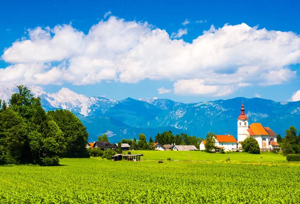 Beau village alpin en Slovénie. Montagnes et ciel nuageux. Le pré vert et la vieille église — Photo