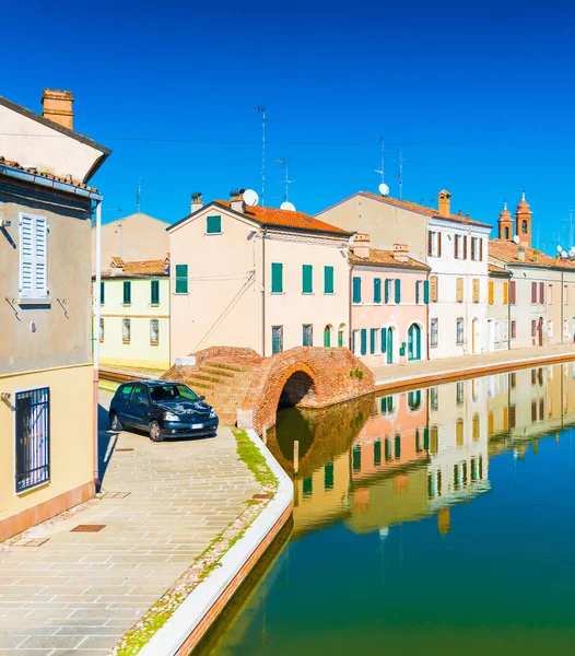 Улица маленького итальянского городка Комаккио. Цветные дома отражаются в воде. Каменный мост и водный канал в венецианском стиле . — стоковое фото