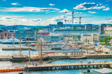 Oslo - Haziran 2019, Norveç: Modern ve tarihi gemilerle Oslo limanının havadan görünüşü. Modern liman, mimari, kule vinçleri, yürüyen insanlarla dolu rıhtımlar, tepeler ve mavi gökyüzü.