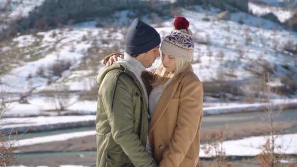 Pareja joven abrazándose con hermosas montañas nevadas en el fondo . — Vídeos de Stock