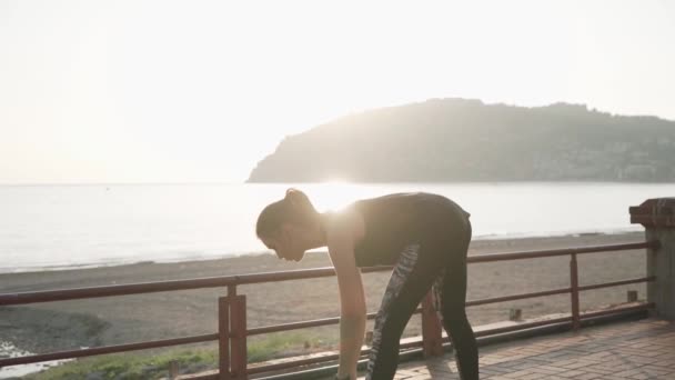 Chica estirándose al atardecer en la playa. Movimiento lento . — Vídeos de Stock