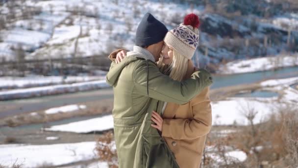 Pareja joven abrazándose con hermosas montañas nevadas en el fondo . — Vídeo de stock