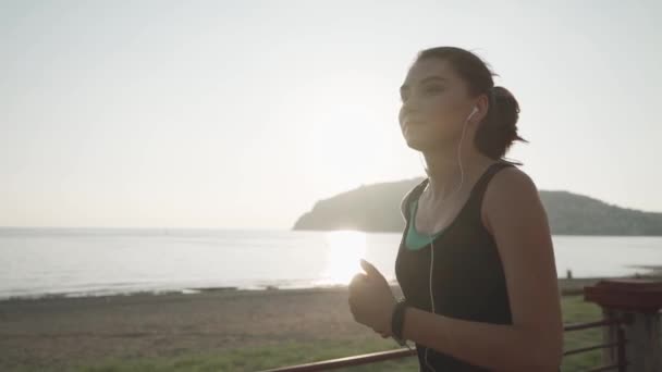 Correr al atardecer en el paseo marítimo. La chica que corre la orilla del mar . — Vídeo de stock