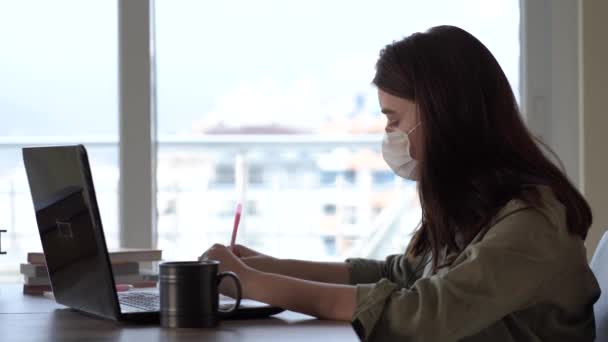 Mujer que trabaja en casa con máscara médica en la cara — Vídeos de Stock