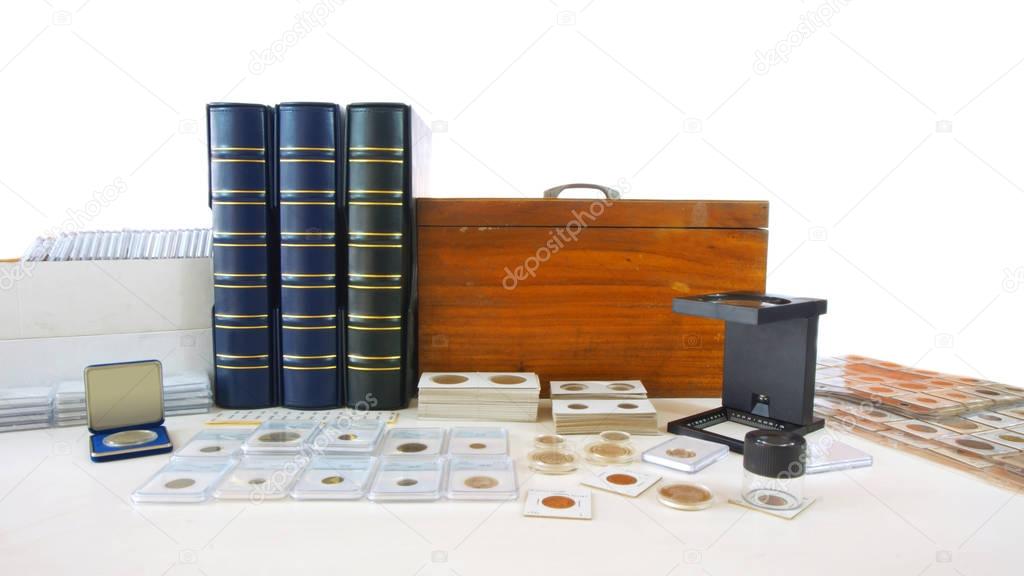 Coins of different countries of the world on white table with folders and supplies background - Numismatic scene