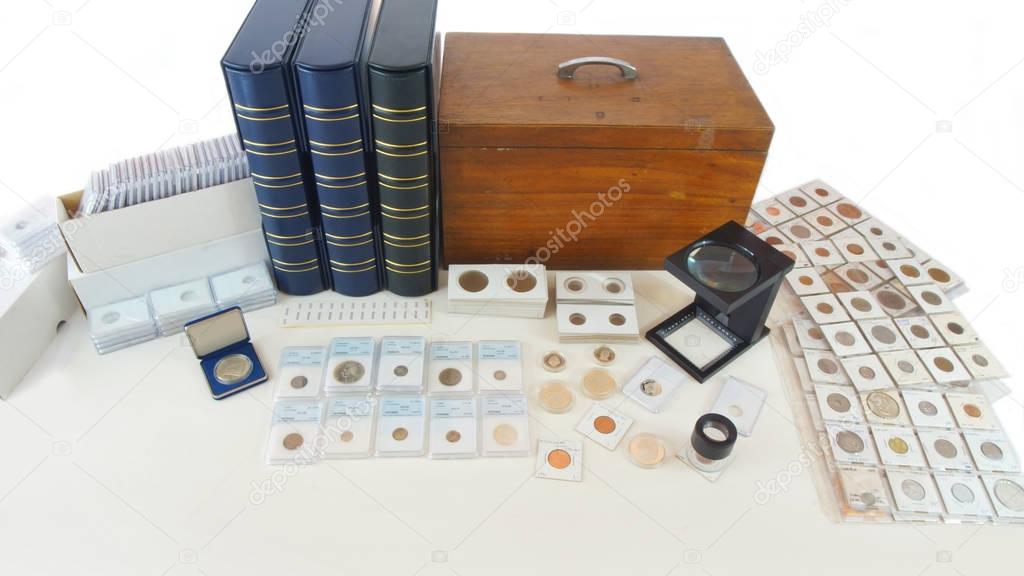 Coins of different countries of the world on white table with folders and supplies background - Numismatic scene