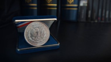 Bağlayıcılar ve kitap içinde belgili tanımlık geçmiş - Nümismatik sahne ile siyah bir tabloda eski 1 dolar gümüş sikke