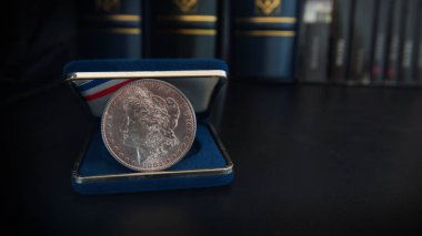 Bağlayıcılar ve kitap içinde belgili tanımlık geçmiş - Nümismatik sahne ile siyah bir tabloda eski 1 dolar gümüş sikke