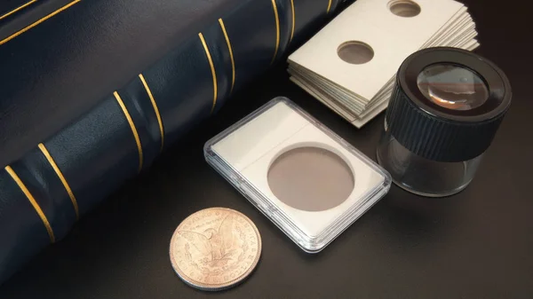 Alter amerikanischer Silberdollar auf schwarzem Tisch mit Lupe, numismatischem Zubehör und Münzalbum - numismatische Szene — Stockfoto