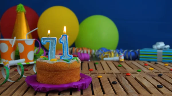 Renkli Balonlar, hediyeler, plastik bardak ve şeker ile mavi duvar arka planda arka plan rustik ahşap masada mumlarla doğum günü pastası. Kek üzerine odaklanmıştır — Stok fotoğraf