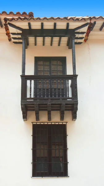 Balcón y ventana de madera con barras de hierro forjado en pared blanca con techo de baldosas —  Fotos de Stock