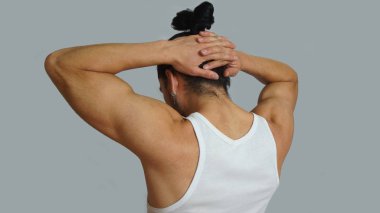 Toplanan saçlarını arkadan elleriyle ense üzerinde birlikte görülen beyaz kolsuz tişört yay genç İspanyol adamla