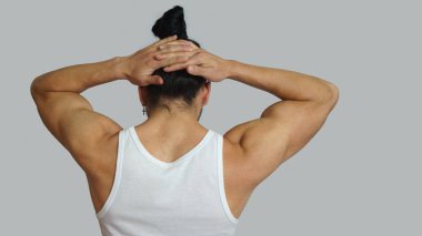 Toplanan saçlarını arkadan elleriyle ense üzerinde birlikte görülen beyaz kolsuz tişört yay genç İspanyol adamla