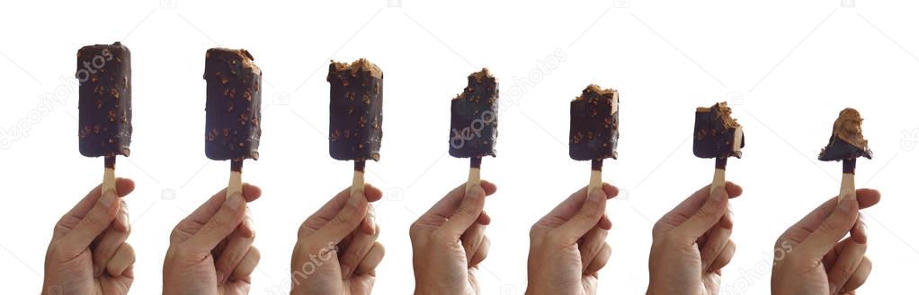 Sequence of an ice cream being eaten step by step. Man's hand holding a vanilla ice cream coated with chocolate peanut over white background