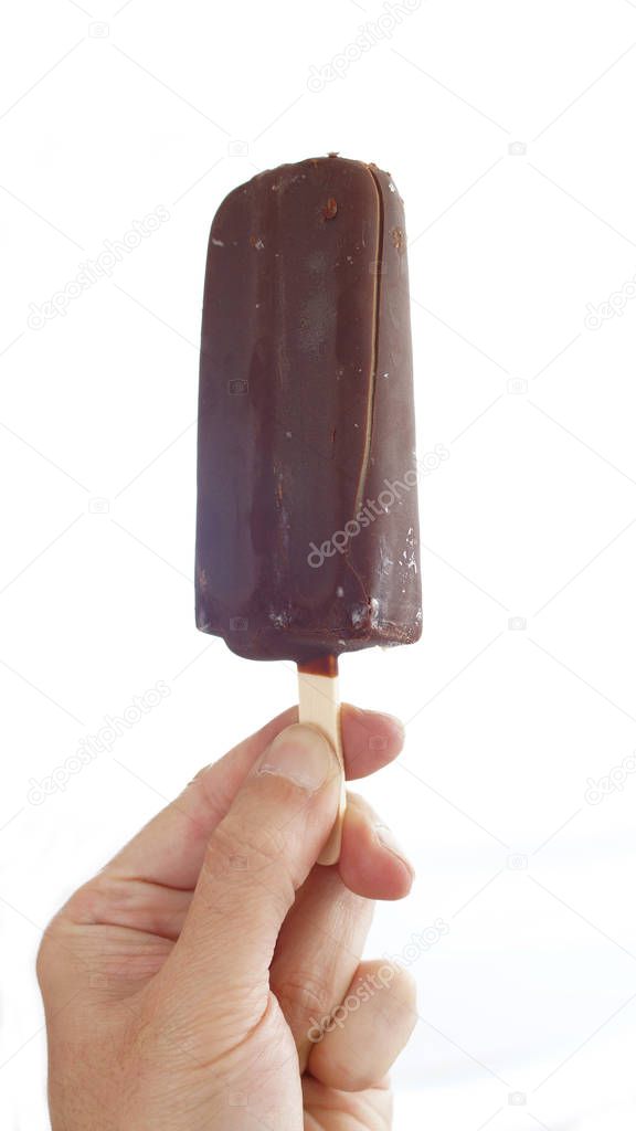 Hand of man holding a chocolate coated vanilla ice cream palette on white background