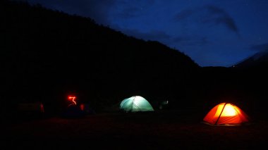 Yıldızlı gece ile moor bulunan ışıklı çadır kamp gece görünümü